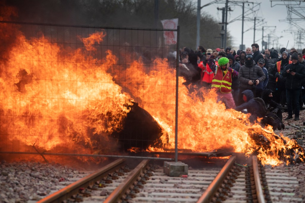 Protesters set up a flaming barricade across railway tracks at a train station during a demonstration after the government pushed a pensions reform through parliament without a vote, using the article 49.3 of the constitution, in Lorient, in Brittany, western France, on March 28, 2023. - France faces another day of strikes and protests nearly two weeks after the president bypassed parliament to pass a pensions overhaul that is sparking turmoil in the country, with unions vowing no let-up in mass protests to get the government to back down. The day of action is the tenth such mobilisation since protests started in mid-January against the law, which includes raising the retirement age from 62 to 64. (Photo by FRED TANNEAU / AFP)