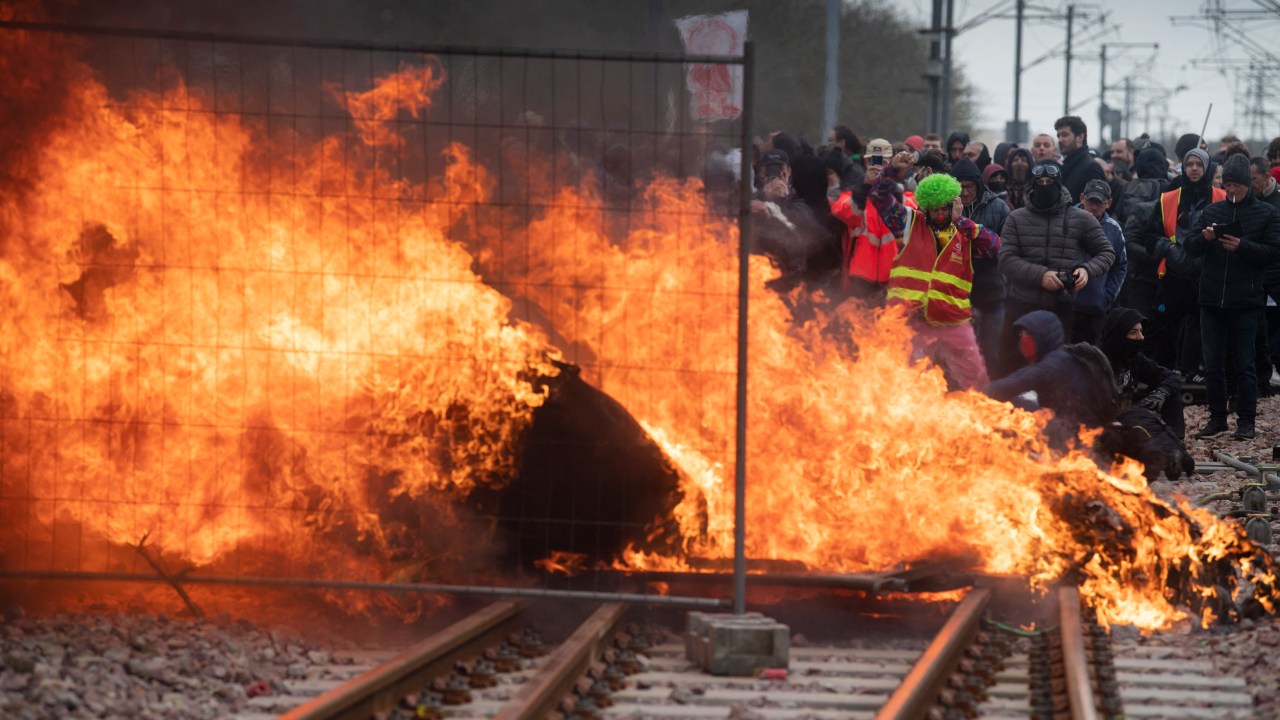 Protesters set up a flaming barricade across railway tracks at a train station during a demonstration after the government pushed a pensions reform through parliament without a vote, using the article 49.3 of the constitution, in Lorient, in Brittany, western France, on March 28, 2023. - France faces another day of strikes and protests nearly two weeks after the president bypassed parliament to pass a pensions overhaul that is sparking turmoil in the country, with unions vowing no let-up in mass protests to get the government to back down. The day of action is the tenth such mobilisation since protests started in mid-January against the law, which includes raising the retirement age from 62 to 64. (Photo by FRED TANNEAU / AFP)