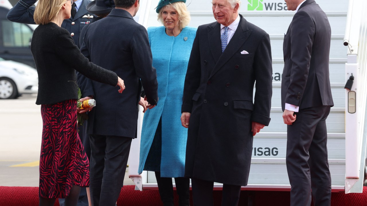 Britain's King Charles III (2R) and Britain's Camilla, Queen Consort (C) are greeted as they disembark their plane after landing at Berlin Brandenburg Airport in Schoenefeld near Berlin, on March 29, 2023. - Britain's King Charles III began his first state visit, having postponed a trip to France due to widespread political protests. Charles will undertake engagements in the German capital and in Brandenburg before heading to Hamburg during the three-day tour. (Photo by Ian Vogler / POOL / AFP)