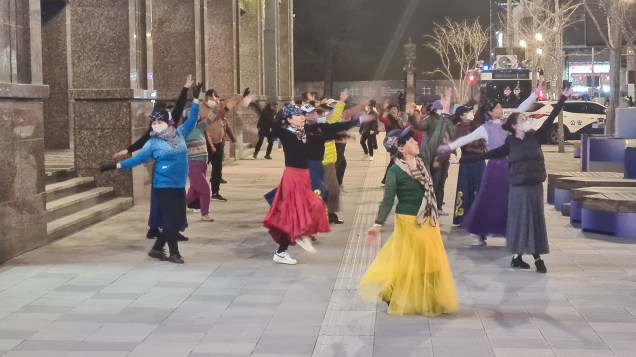 DOIS PARA LÁ, DOIS PARA CÁ - Mulheres dançam na rua Wangfujing , centro de Pequim: a face dócil de uma China que range os dentes para o mundo ocidental