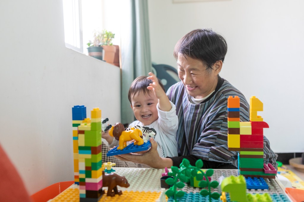 Grandmother enjoy having fun with young grandson by game table