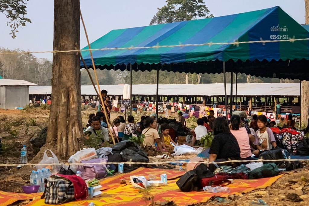 People fleeing fighting between the Myanmar military and ethnic rebel groups shelter on the Thai side of the Moei river, in Mae Sot district in Tak province on April 7, 2023. - Thousands of people have fled into Thailand following fierce fighting between Myanmar rebels and the military, Thai officials said on April 6. (Photo by AFP)