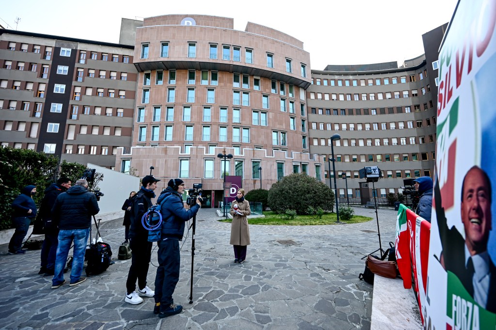 A banner reading "Go Silvio!" is seen as journalists wait outside the San Raffaele hospital where former Italian Prime Minister, Silvio Berlusconi is hospitalised at San Raffaele hospital in Milan on April 8, 2023. - The 86-year-old media mogul and senator, who is currently in intensive care suffering from leukaemia and a lung infection, was showing signs of improvement, his brother said. (Photo by Piero CRUCIATTI / AFP)