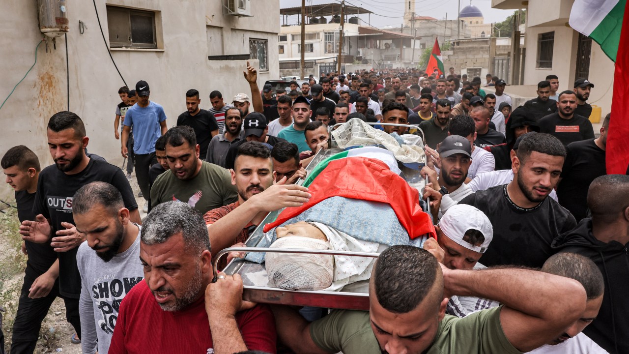 EDITORS NOTE: Graphic content / Mourners march with the body of Palestinian teenager Mohamed Fayez Balhan, 15, during his funeral in the Aqabat Jaber camp for Palestinian refugees near Jericho in the occupied West Bank on April 10, 2023, after he was killed during a Israeli raid in the camp. (Photo by AHMAD GHARABLI / AFP)