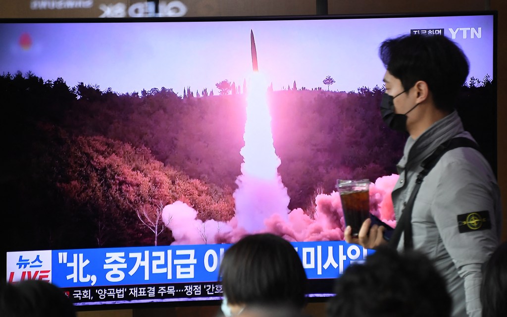 A man walks past a television screen showing a news broadcast with file footage of a North Korean missile test, at a railway station in Seoul on April 13, 2023. - North Korea fired a ballistic missile on April 13, Seoul's military said, prompting Japan to briefly issue a seek shelter warning to residents of the northern Hokkaido region. (Photo by Jung Yeon-je / AFP)