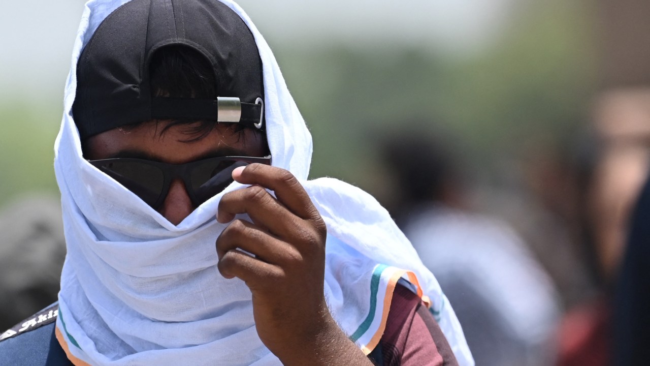 A man uses a scarf to shelter from the heat during a hot day in New Delhi on April 19, 2023. (Photo by Arun SANKAR / AFP)