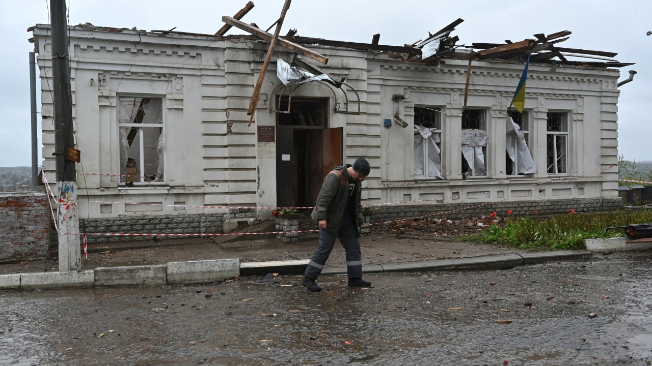 A municipal worker walks in front of the local history museum destroyed following Russian missile strike in the town of Kupiansk, Kharkiv region on April 25, 2023, amid the Russian invasion of Ukraine. - President Volodymyr Zelensky on April 25 said Russia was trying to erase Ukraine's history and culture after a strike on a museum killed one employee and wounded 10. (Photo by SERGEY BOBOK / AFP)