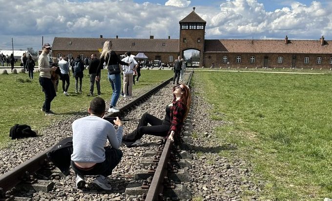Uma turista posa para uma foto em frente ao Museu Estadual de Auschwitz-Birkenau, na Polônia.
