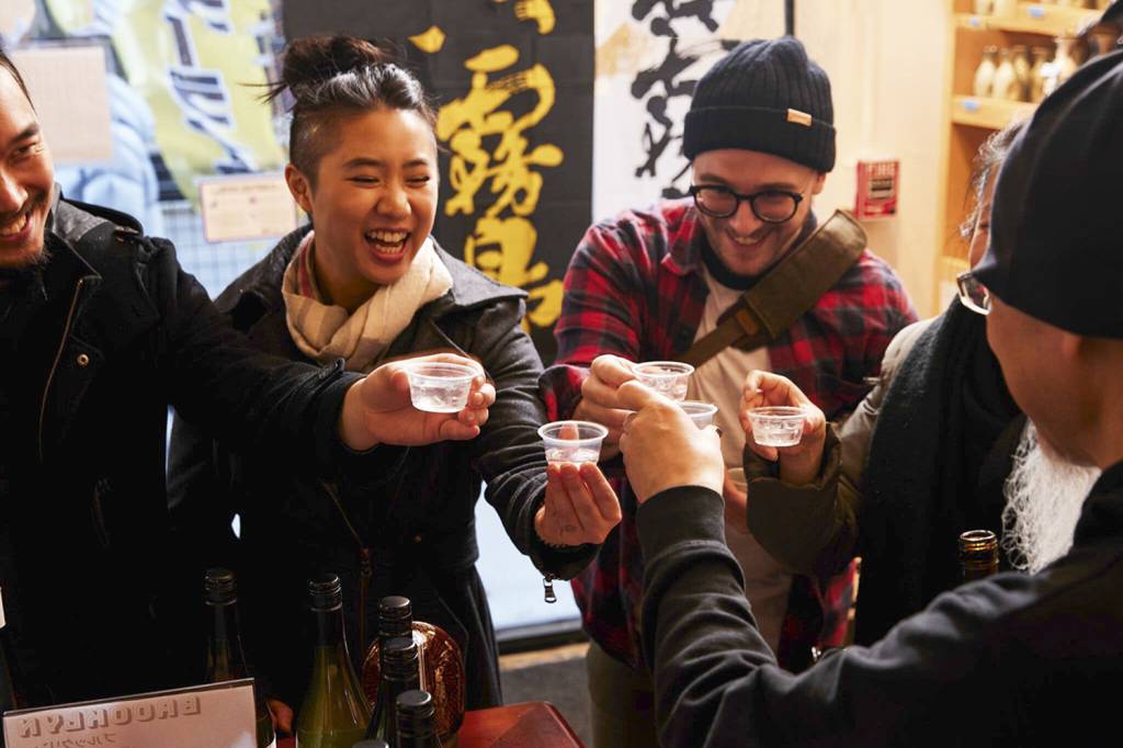 RITUAL MILENAR - Amigos brindam em um izakaya (bar japonês) do bairro do Brooklyn, em Nova York: a etiqueta exige que ninguém sirva o próprio copo e que todos gritem kanpai (saúde) antes de começar a beber o fermentado