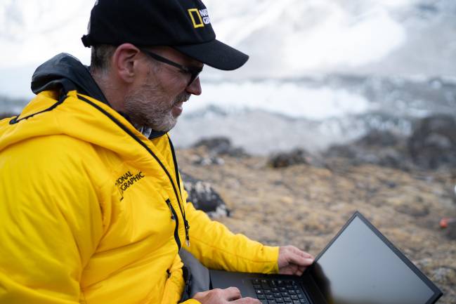 Mount Everest, Nepal - 2019/04/28: Alex Tait works on a laptop while installing mapping hardware. Image taken near Everest Base Camp. The National Geographic and Rolex Perpetual Planet Everest Expedition was the most comprehensive single scientific expedition to the mountain in history. A diverse team of scientists, storytellers, and expert climbers and guides surveyed the mountain's geography, geology and biodiversity; installed a network of weather stations, including the world's highest; and collected ice and lake cores, all in order to better understand the impacts of climate change on the world's tallest mountain.