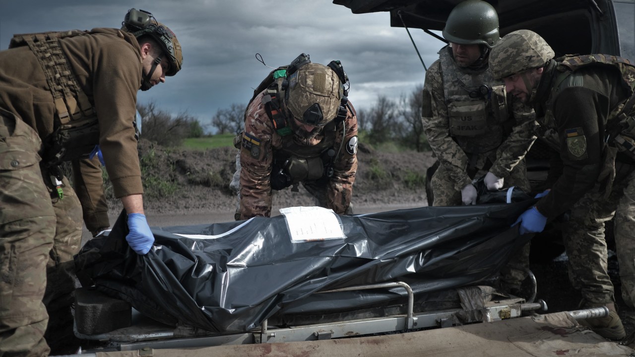 Ukrainian servicemen and paramedics load a bag containing a body into a medical evacuation vehicle on a road near Bakhmut, Donetsk region, on April 25, 2023, amid Russian invasion of Ukraine. (Photo by Sergey SHESTAK / AFP)