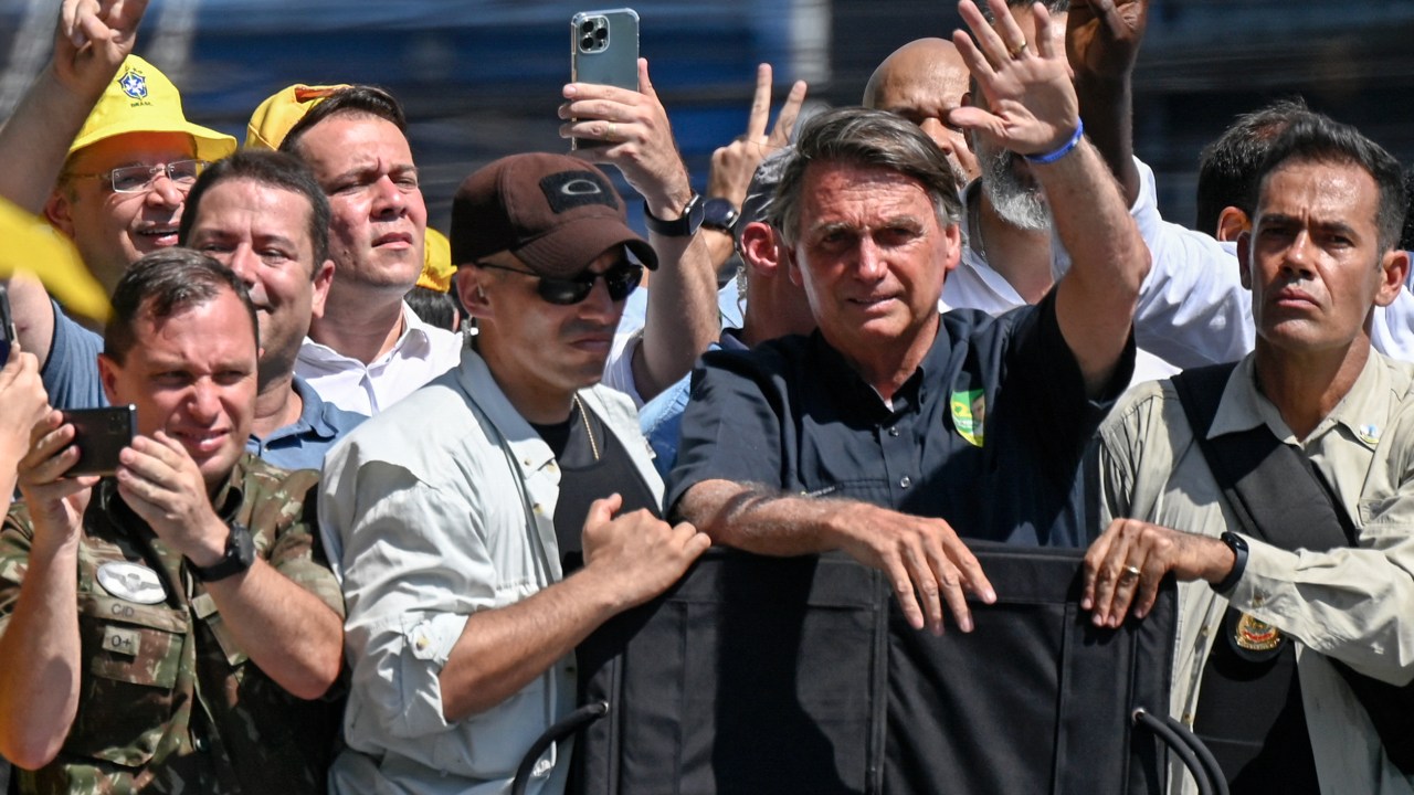 (FILES) Brazilian president and re-election candidate Jair Bolsonaro (2-R), accompanied by personal assistantarmy officer Mauro Cid (L) and bodyguards, waves at supporters during a campaign rally in Sao Joao de Meriti, Rio de Janeiro, Brazil on September 27, 2022. - Police in Brazil searched ex-president Jair Bolsonaro's home on May 3, 2023, as part of an investigation into allegations of falsifying COVID-19 vaccination certificates, media reports said. The far-right ex-president (2019-2022), who faced widespread criticism for his unorthodox handling of the pandemic, has repeatedly said he is not vaccinated against COVID-19 .Media reports said police had arrested a top Bolsonaro aide, army officer Mauro Cid. (Photo by MAURO PIMENTEL / AFP)