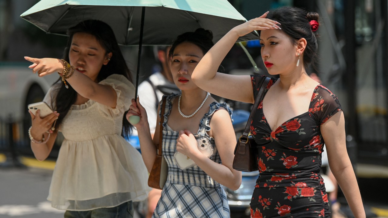 Women use an umbrella to shelter from the sun amid hot weather in Shanghai on May 29, 2023. Shanghai on May 29 recorded its hottest May day in 100 years, the city's meteorological service announced, shattering the previous high by a full degree. (Photo by AFP) / China OUT