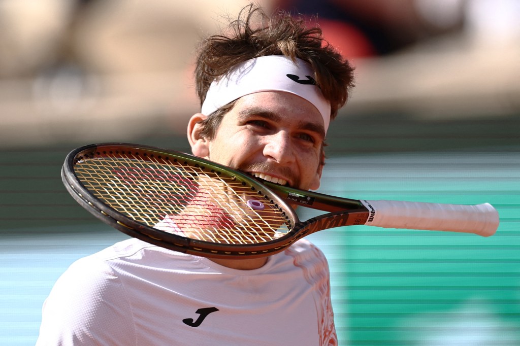 Brazil's Thiago Seyboth Wild bites his racket during his match against Russia's Daniil Medvedev during their men's singles match on day three of the Roland-Garros Open tennis tournament at the Court Philippe-Chatrier in Paris on May 30, 2023. (Photo by Anne-Christine POUJOULAT / AFP)