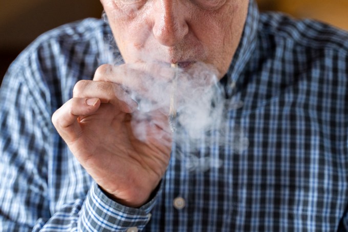 Senior man at home smoking marihuana joint