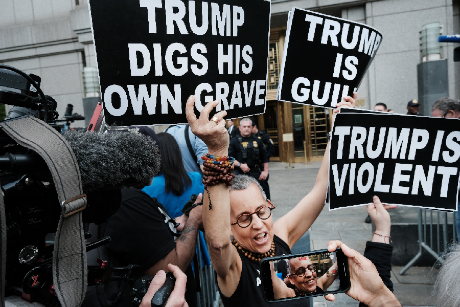A protester holds up signs moments before writer E. Jean Carroll leaves a Manhattan court house after a jury found former President Donald Trump liable for sexually abusing her in a Manhattan department store in the 1990's