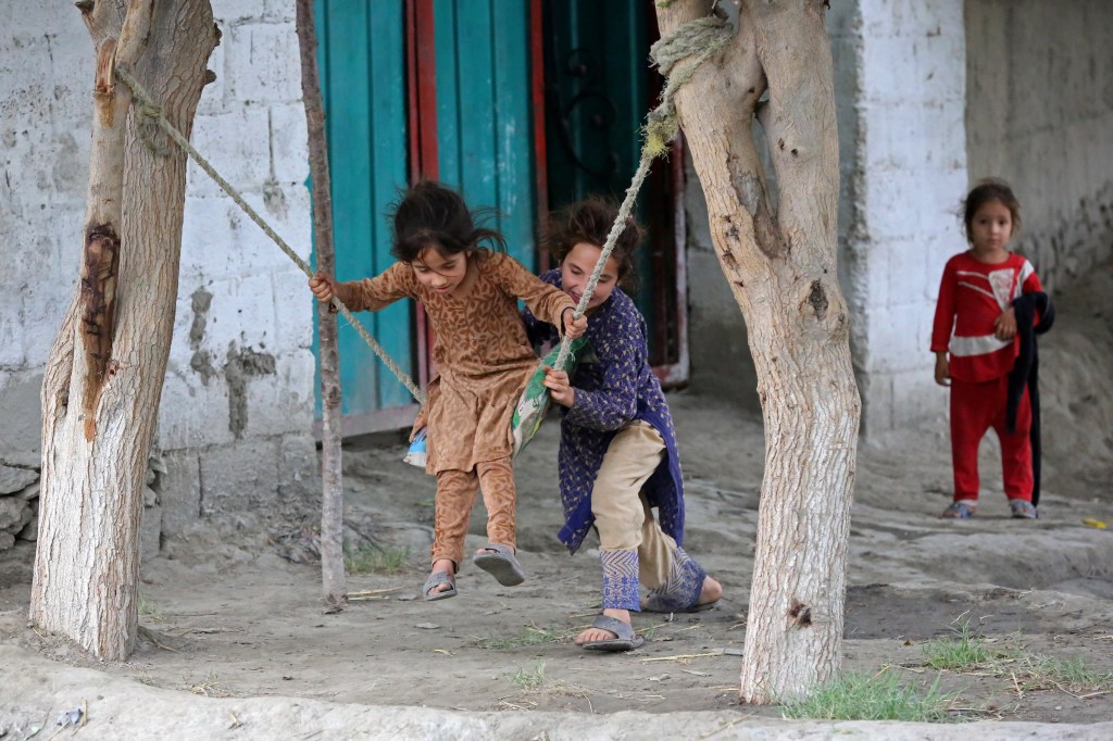 Girls play on swings in front of their house in Jalalabad on May 30, 2023. (Photo by Shafiullah KAKAR / AFP)