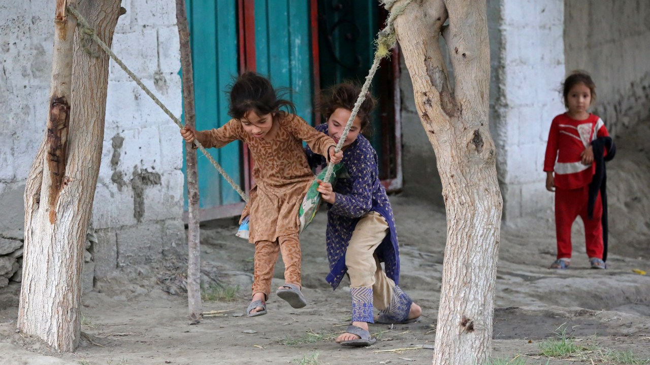 Girls play on swings in front of their house in Jalalabad on May 30, 2023. (Photo by Shafiullah KAKAR / AFP)