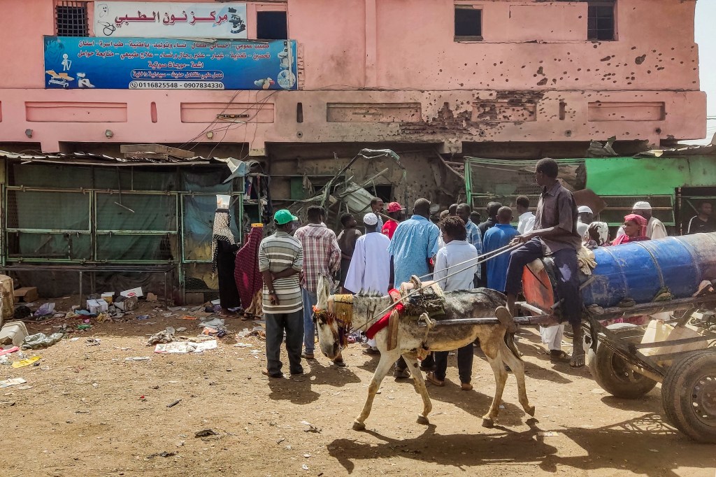 People gather by a medical centre building riddled with bullet holes at the Souk Sitta (Market Six) in the south of Khartoum on June 1, 2023. Shelling and aerial bombardments killed 18 civilians at a market in Sudan's capital where fighting showed no signs of abating on June 1, after the army abandoned truce talks. For more than six weeks, Khartoum and other parts of the country have been gripped by bloody warfare between the army and the paramilitary Rapid Support Forces. (Photo by AFP)