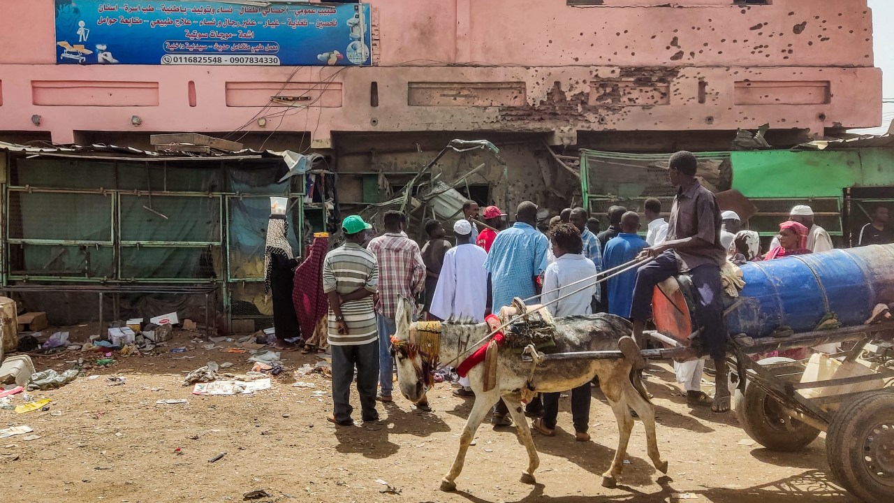 People gather by a medical centre building riddled with bullet holes at the Souk Sitta (Market Six) in the south of Khartoum on June 1, 2023. Shelling and aerial bombardments killed 18 civilians at a market in Sudan's capital where fighting showed no signs of abating on June 1, after the army abandoned truce talks. For more than six weeks, Khartoum and other parts of the country have been gripped by bloody warfare between the army and the paramilitary Rapid Support Forces. (Photo by AFP)