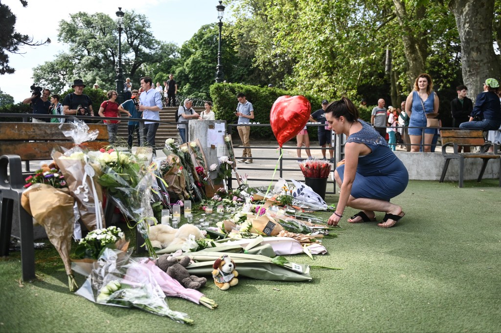 A woman lays flowers for the victims of a stabbing attack that occured the day before in the 'Jardins de l'Europe' parc in Annecy, French Alps, on June 9, 2023. A man armed with a knife stabbed four preschool children and injured two adults by a lake in the French Alps on June 8 in an attack that sent shock waves through the country. The suspect is a Syrian in his early 30s who was granted refugee status in Sweden in April, a police source told AFP. He was arrested at the scene. (Photo by OLIVIER CHASSIGNOLE / AFP)