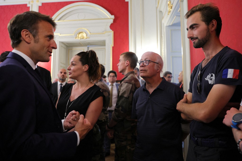 French President Emmanuel Macron (L) talks with Henri (R), the 24-year-old known as the 'backpack hero', who suffered minor stab wounds as he tried to stop the fleeing suspect, during a meeting with rescue forces at the Haute-Savoie prefecture, a day after a mass stabbing in a park, in Annecy, in the French Alps, France, on June 9, 2023. A Syrian refugee suspected of stabbing six people in the French Alpine town of Annecy on June 8, 2023 did not appear to have a "terrorist motive", the local prosecutor told reporters. Prosecutor Line Bonnet-Mathis said that of the four children injured in the assault, one was aged just 22 months, two were two-year-olds, and the eldest was three. (Photo by DENIS BALIBOUSE / POOL / AFP)