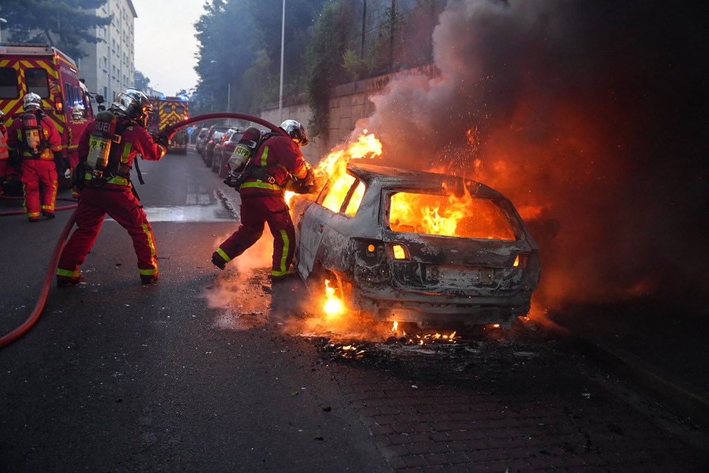 Firefighters work to put out a burning car on the sidelines of a demonstration in Nanterre, west of Paris, on June 27, 2023, after French police killed a teenager who refused to stop for a traffic check in the city. The 17-year-old was in the Paris suburb early on June 27 when police shot him dead after he broke road rules and failed to stop, prosecutors said. The event has prompted expressions of shock and questions over the readiness of security forces to pull the trigger. (Photo by Zakaria ABDELKAFI / AFP)