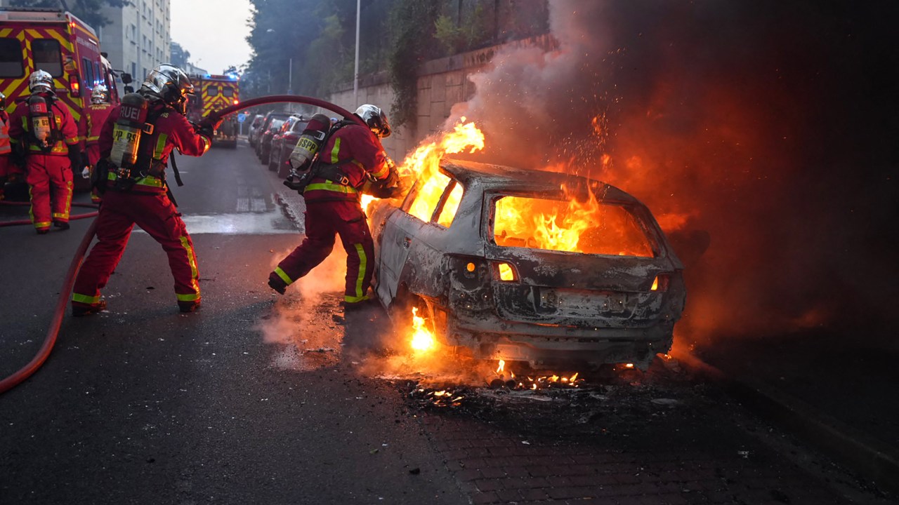 Firefighters work to put out a burning car on the sidelines of a demonstration in Nanterre, west of Paris, on June 27, 2023, after French police killed a teenager who refused to stop for a traffic check in the city. The 17-year-old was in the Paris suburb early on June 27 when police shot him dead after he broke road rules and failed to stop, prosecutors said. The event has prompted expressions of shock and questions over the readiness of security forces to pull the trigger. (Photo by Zakaria ABDELKAFI / AFP)