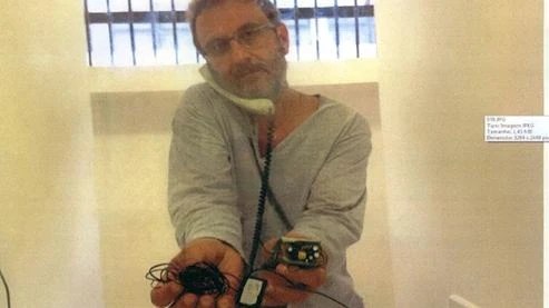 O doleiro Alberto Youssef exibe aparelho de escuta encontrado em sua cela