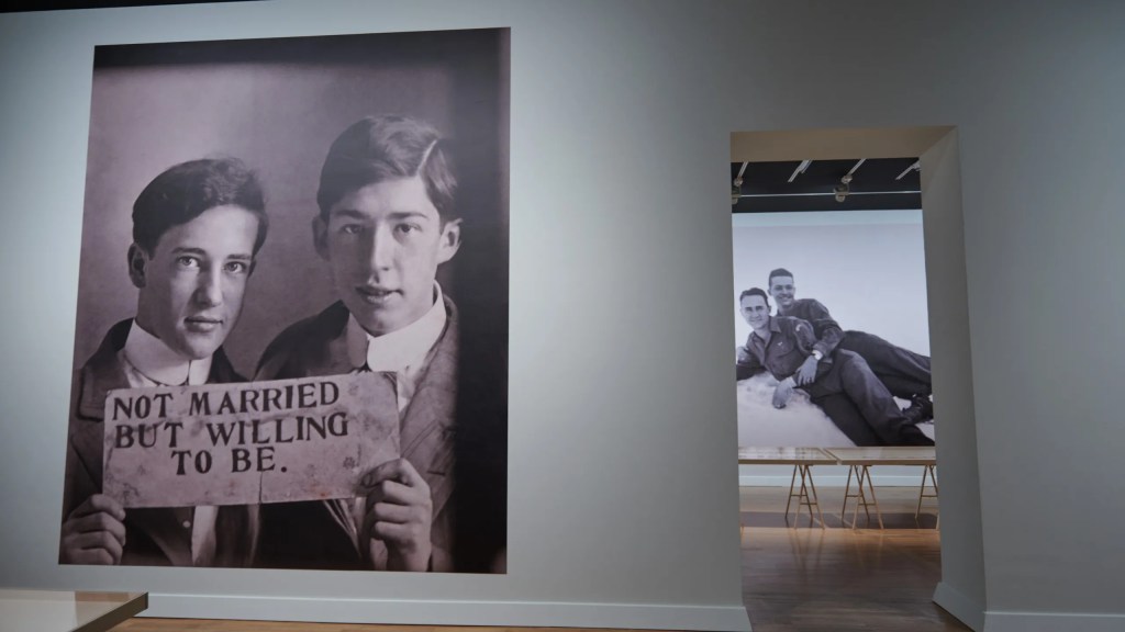 Em uma das fotos da exibição dois homens seguram um cartaz em que se lê 