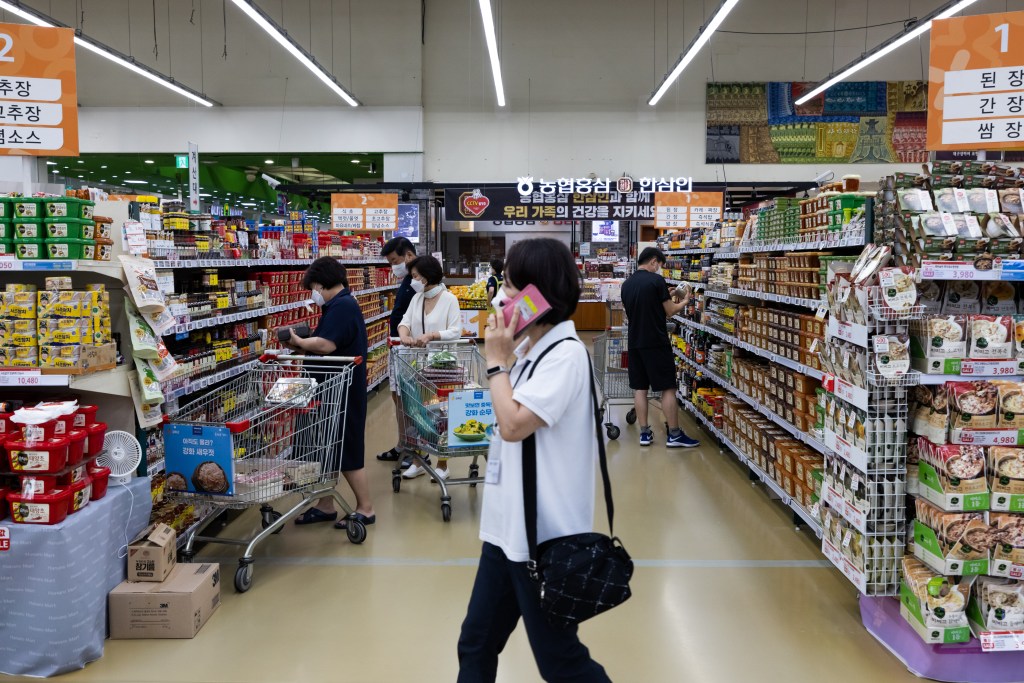 Customers wear protective masks while shopping at a Hanaro Mart supermarket, operated by the National Agricultural Cooperative Federation (Nonghyup), in the Seocho district of Seoul, South Korea, on Friday, Aug. 20, 2021. Focus is growing on whether the Bank of Korea can take the country's worst-ever virus wave in stride and tighten monetary policy on Aug. 26. Photographer: SeongJoon Cho/Bloomberg via Getty Images