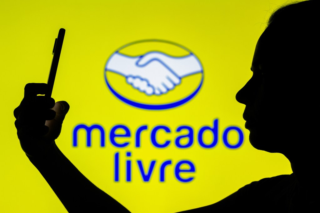 BRAZIL - 2022/04/22: In this photo illustration, the Mercado Livre logo is seen in the background of a silhouetted woman holding a mobile phone. (Photo Illustration by Rafael Henrique/SOPA Images/LightRocket via Getty Images)