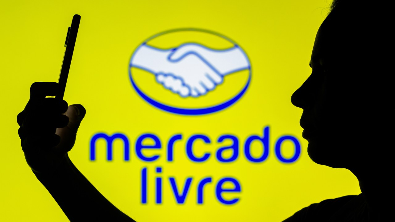 BRAZIL - 2022/04/22: In this photo illustration, the Mercado Livre logo is seen in the background of a silhouetted woman holding a mobile phone. (Photo Illustration by Rafael Henrique/SOPA Images/LightRocket via Getty Images)