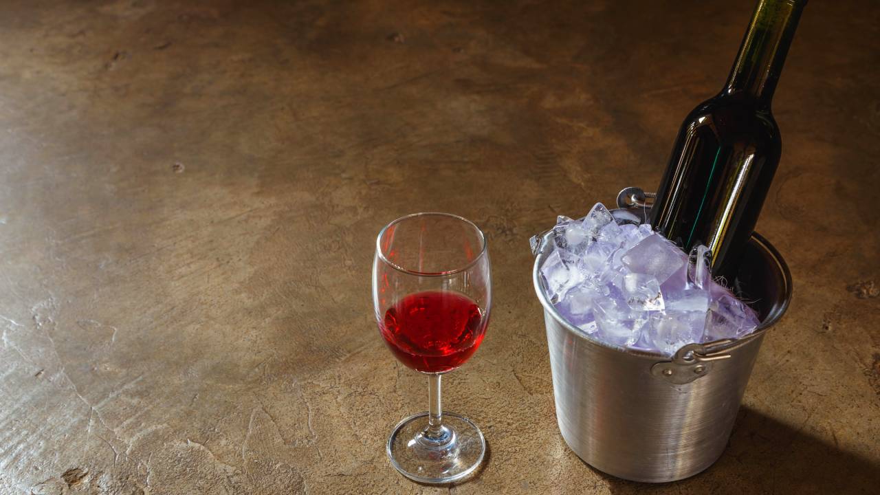 bottle of red wine in an ice bucket and a glass of red wine