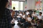 Teacher teaching children in school uniform to play music with Maracas in school
