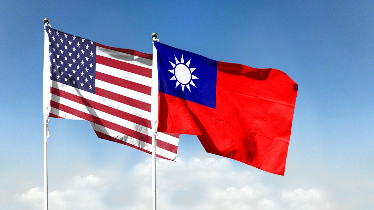 Bandeiras americana e taiwanesa balançando em um céu azul.