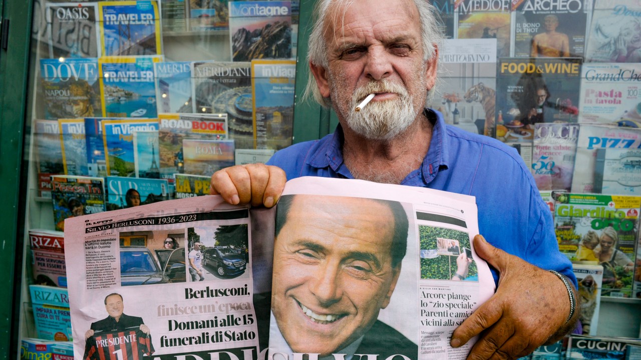 A man poses for a photo after reading La Gazzetta dello Sport newspaper with images of former Italian Prime Minister Silvio Berlusconi on June 13, 2023 in Livorno, Italy
