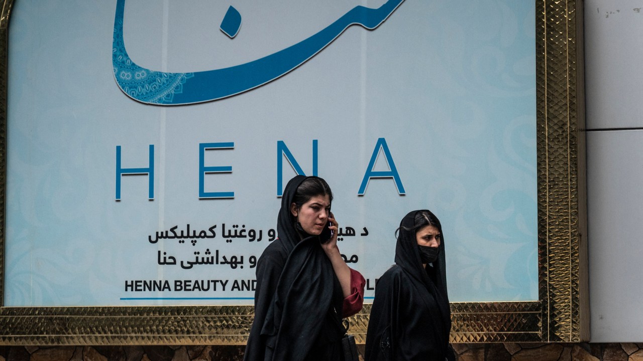 Women walks past a beauty salon at the Shahr-e Naw area in Kabul on July 4, 2023. Afghanistan's Taliban authorities have ordered beauty parlours across the country to shut within a month, the vice ministry confirmed on July 4, the latest curb to further squeeze women out of public life. (Photo by Wakil KOHSAR / AFP)