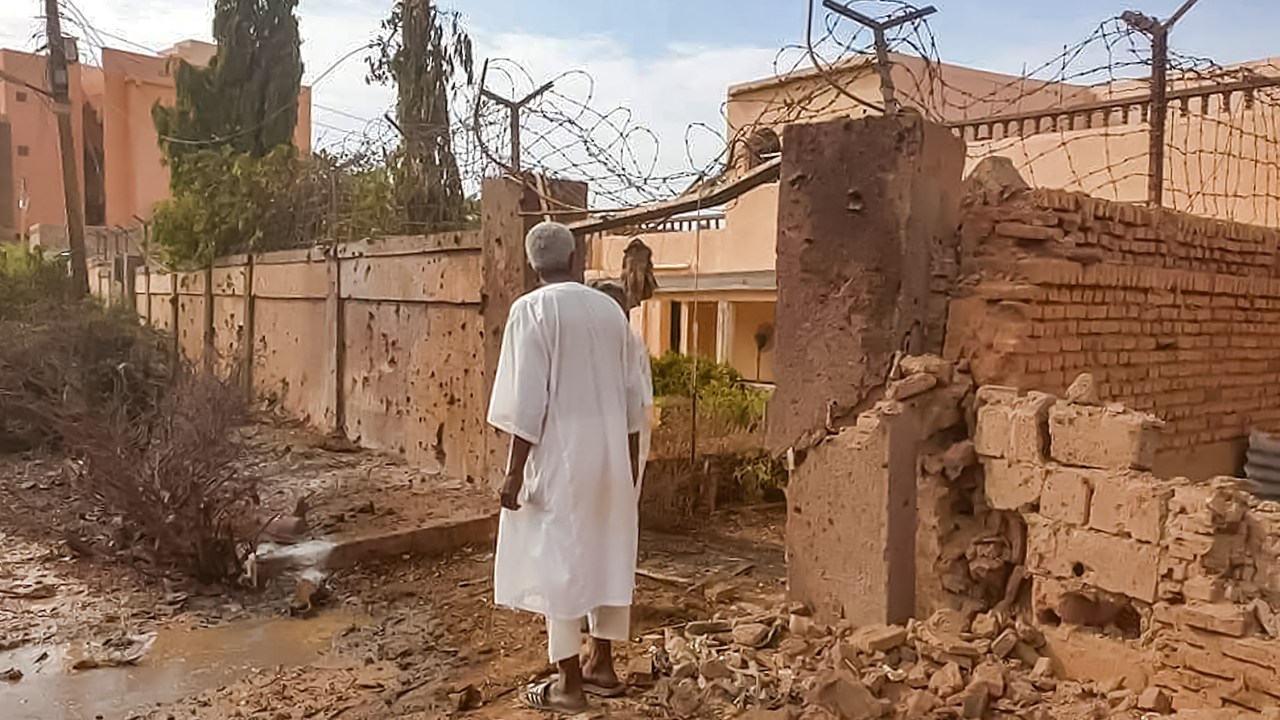 A man walks through rubble by a bullet-riddled fence with barbed-wire, in the aftermath of clashes and bombardment in the Ombada suburb on the western outskirts of Omdurman, the twin-city of Sudan's capital, on July 4, 2023. Heavy fighting raged on July 4 across the Sudanese capital where witnesses reported a fighter-jet being shot down and artillery and machine gun fire rocking several neighbourhoods. (Photo by AFP)