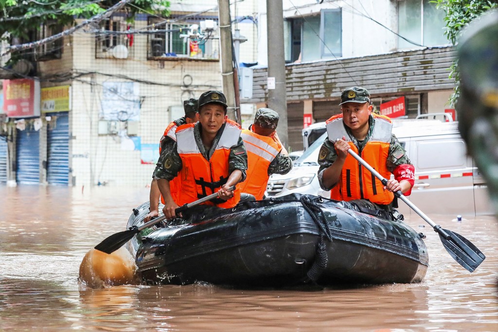 (FILES) This file photo taken on July 4, 2023 shows paramilitary policemen searching an area after it was flooded by heavy rains in China's southwestern Chongqing. Fifteen people have been killed and four are missing after torrential rain in southwest China, state media said on July 5, 2023. (Photo by AFP) / China OUT