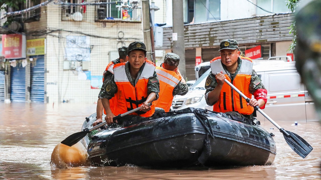 (FILES) This file photo taken on July 4, 2023 shows paramilitary policemen searching an area after it was flooded by heavy rains in China's southwestern Chongqing. Fifteen people have been killed and four are missing after torrential rain in southwest China, state media said on July 5, 2023. (Photo by AFP) / China OUT