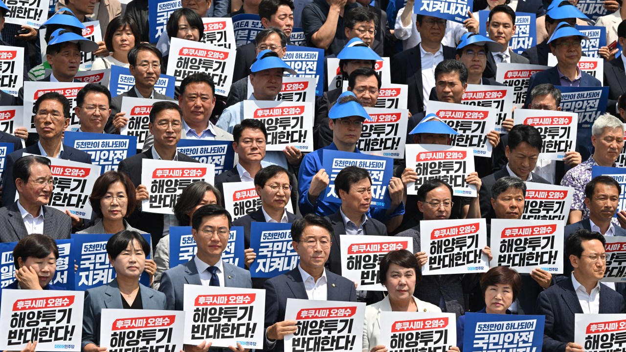 South Korea's main opposition Democratic Party lawmakers and party members hold placards reading "We oppose the dumping of Fukushima contaminated water into the sea" during a rally against Japan's plan to release treated water from the Fukushima nuclear plant, at the National Assembly in Seoul on July 7, 2023. (Photo by Jung Yeon-je / AFP)