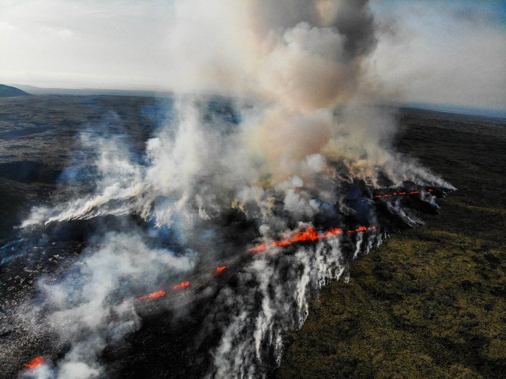 This aerial photograph taken on July 10, 2023 shows smoke billowing from flowing lava during an volcanic eruption near Litli Hrutur, south-west of Reykjavik in Iceland. A volcanic eruption started on July 10, 2023 around 30 kilometres (19 miles) from Iceland's capital Reykjavik, the country's meteorological office said, marking the third time in two years that lava has gushed out in the area. "The eruption is taking place in a small depression just north of Litli Hrutur, from which smoke is escaping in a north-westerly direction," the office said. Footage circulating in the local media shows a massive cloud of smoke rising from the ground as well as a substantial flow of lava. (Photo by Kristinn Magnusson / AFP) / Iceland OUT