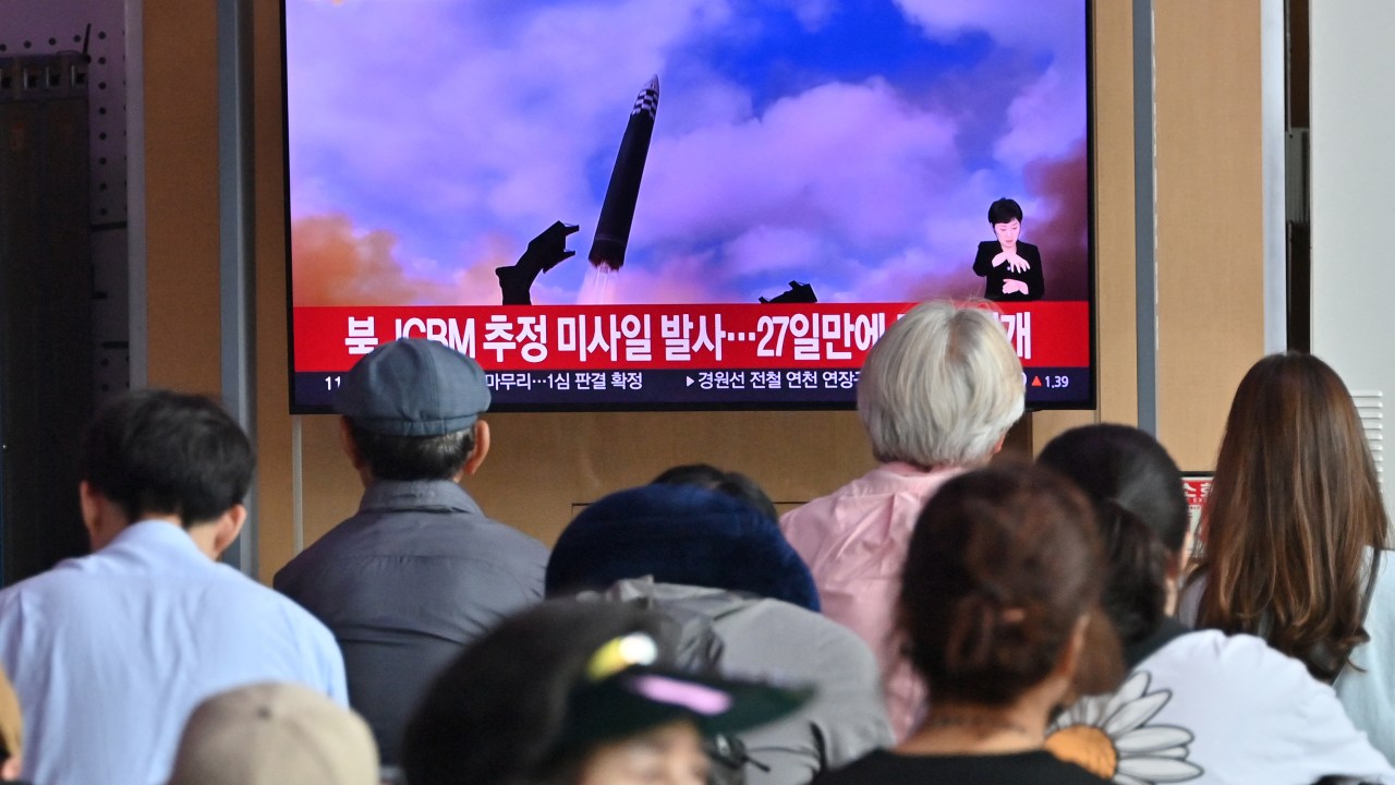 People watch a television screen showing a news broadcast with file footage of a North Korean missile test, at a railway station in Seoul on July 12, 2023. North Korea has fired a suspected long-range ballistic missile, the South Korean military said July 12, days after Pyongyang threatened to down US spy planes that violated its airspace. (Photo by Jung Yeon-je / AFP)
