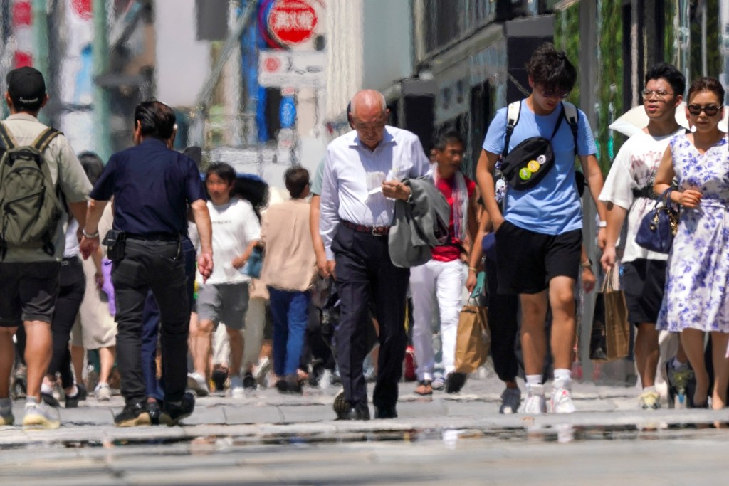 Pedestrians walk during heatwave conditions in Tokyo on July 18, 2023. (Photo by Kazuhiro NOGI / AFP)