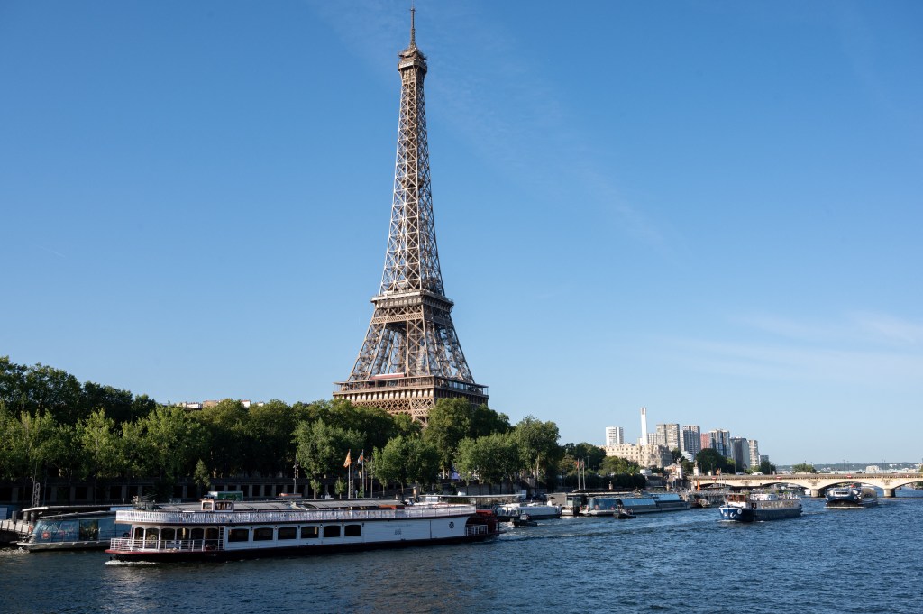 A peniche boat sails past the Eiffel Tower on the River Seine on July 17, 2023, during a parade to test "maneuvers", "distances", "duration" and "video capture" of the future opening ceremony of the Paris Olympics in 2024. For this mini-rehearsal, the total fleet is made up of 57 boats, 39 representing the delegations - slightly less than half as many as for the actual ceremony in 2024 - and 18 others providing support (assistance, first aid) as well as Olympic Broadcasting Services (OBS), the Olympic TV broadcaster. (Photo by BERTRAND GUAY / AFP)