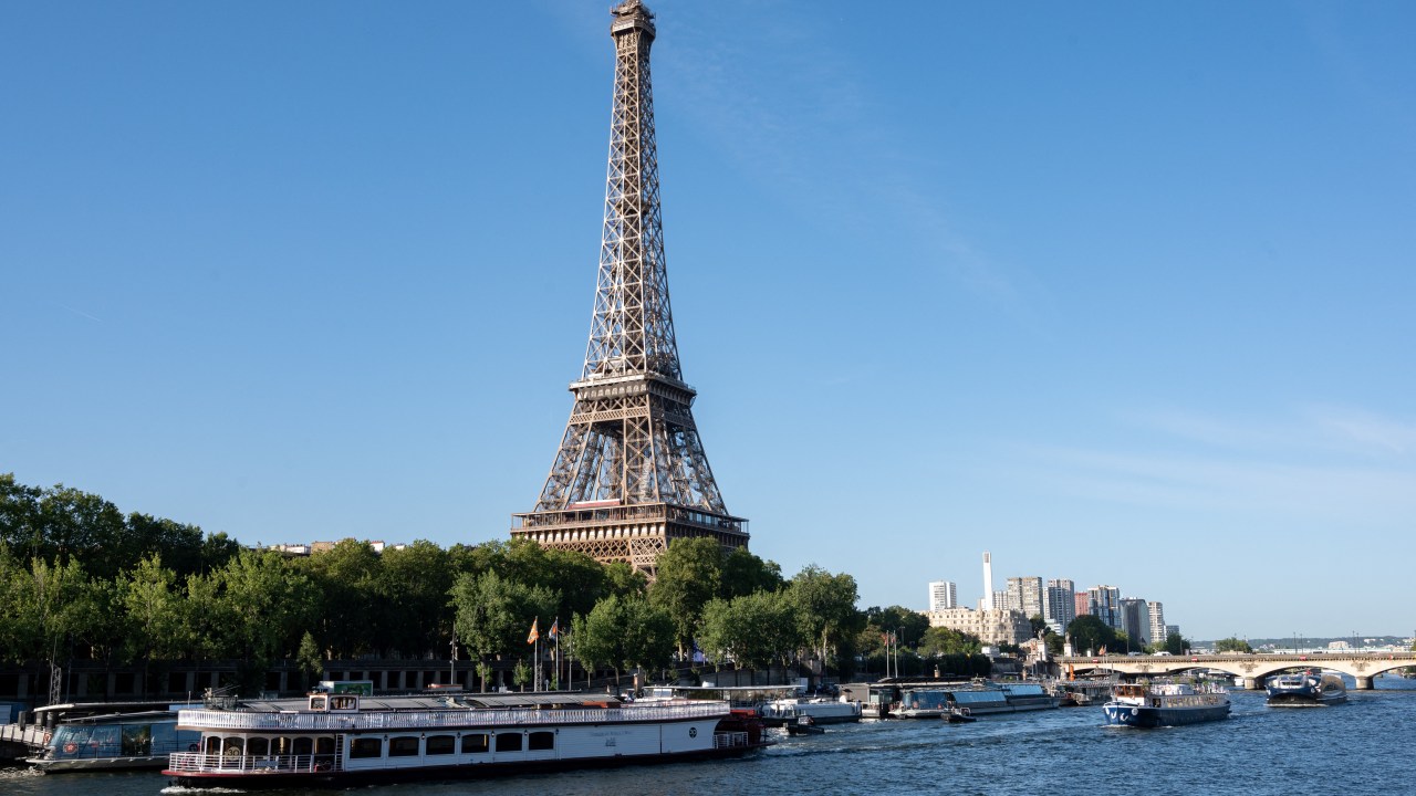 A peniche boat sails past the Eiffel Tower on the River Seine on July 17, 2023, during a parade to test "maneuvers", "distances", "duration" and "video capture" of the future opening ceremony of the Paris Olympics in 2024. For this mini-rehearsal, the total fleet is made up of 57 boats, 39 representing the delegations - slightly less than half as many as for the actual ceremony in 2024 - and 18 others providing support (assistance, first aid) as well as Olympic Broadcasting Services (OBS), the Olympic TV broadcaster. (Photo by BERTRAND GUAY / AFP)