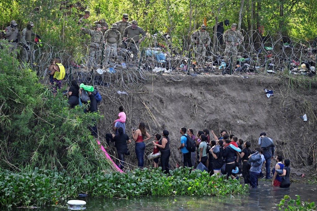 Imigrantes que cruzaram o rio Bravo (Rio Grande nos Estados Unidos) são detidos por membros da Guarda Nacional dos EUA, que reforçam uma cerca de arame farpado na fronteira EUA-México. 10/05/2023