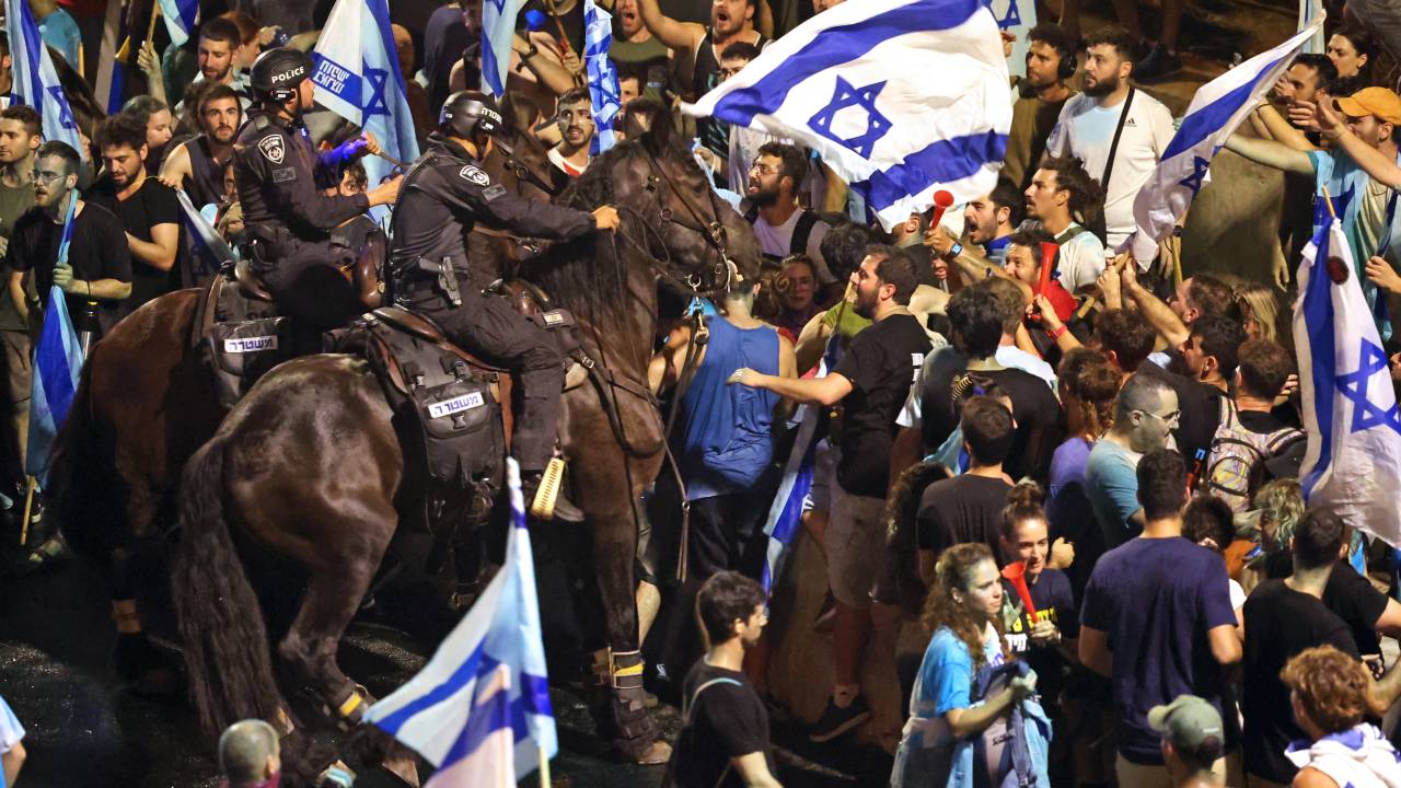 A man carries a woman in arms as demonstrators clash with Israeli riot police during a protest against the Israeli government's judicial reform plan in Tel Aviv on July 24, 2023. Israeli lawmakers on July 24 approved a key clause of a controversial judicial reform plan that aims to curb the powers of the Supreme Court in striking down government decisions. (Photo by JACK GUEZ / AFP)