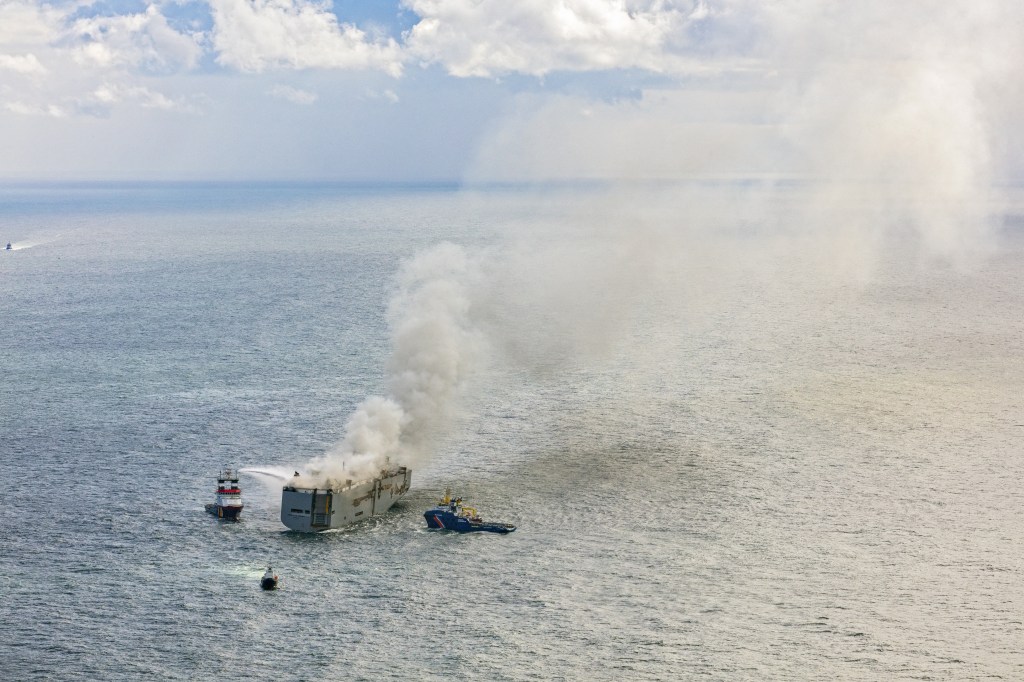 This aerial photograph shows emergency boats extinguishing a fire aboard the Panamanian-registered car carrier cargo ship Fremantle Highway, off the coast of the northern Dutch island of Ameland. One sailor died and several others were injured after a fire broke out on a car carrier ship off the Netherlands on Wednesday, the Dutch coastguard said. Rescue personnel received a call shortly after midnight (2200 GMT Tuesday) saying a fire had started on the Fremantle Highway, a Panamanian-registered ship with 3,000 vehicles on board, about 14.5 nautical miles (27 kilometres) off the northern Dutch island of Ameland. (Photo by Flying Focus / ANP / AFP) / Netherlands OUT